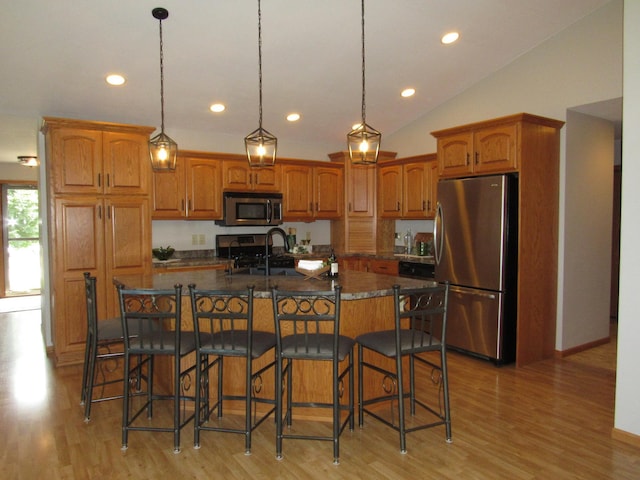 316 8th St NE, Fulda, MN 56131 - kitchen with appliances with stainless steel finishes, brown cabinetry, recessed lighting, a kitchen breakfast bar, and light wood-style floors