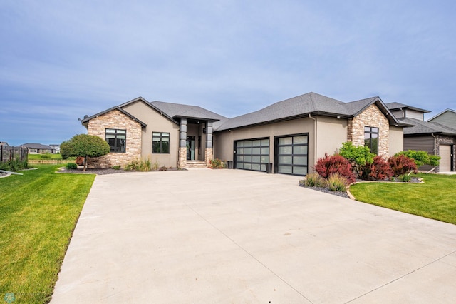 7373 14th St S, Fargo, ND 58104 - view of front of home with stone siding, an attached garage, a front yard, and stucco siding