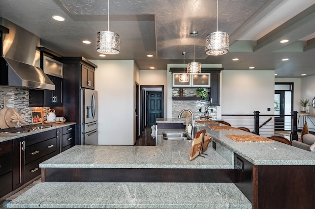 7373 14th St S, Fargo, ND 58104 - kitchen with appliances with stainless steel finishes, ventilation hood, a large island with sink, backsplash, and glass insert cabinets