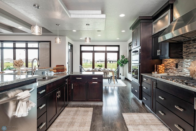 7373 14th St S, Fargo, ND 58104 - kitchen with wall chimney range hood, backsplash, appliances with stainless steel finishes, light stone counters, and dark wood-style floors
