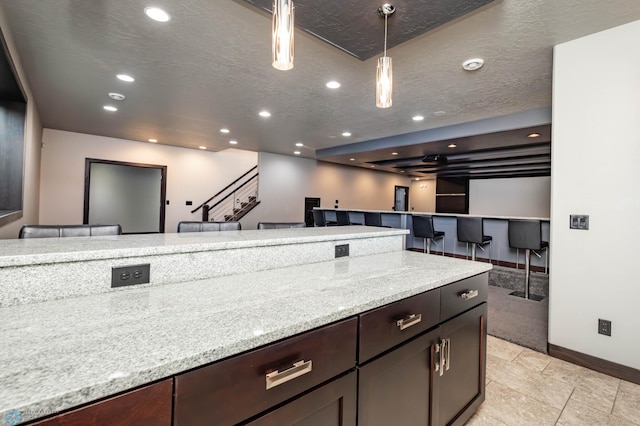 7373 14th St S, Fargo, ND 58104 - kitchen with recessed lighting, open floor plan, hanging light fixtures, dark brown cabinets, and light stone countertops