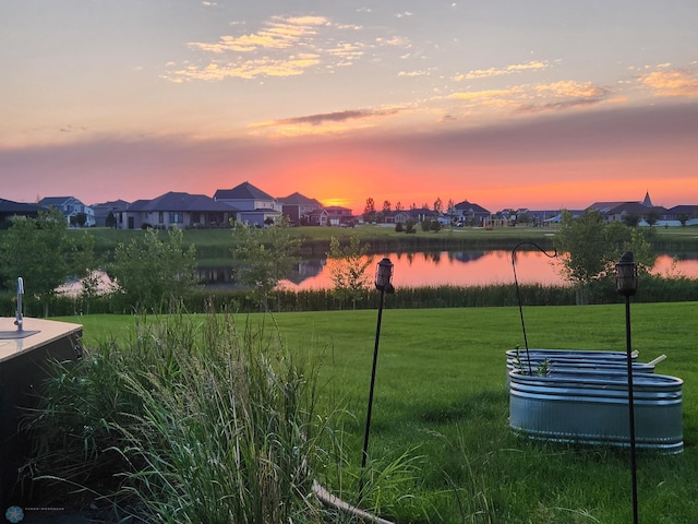 7373 14th St S, Fargo, ND 58104 - yard at dusk with a residential view, a lawn, and a water view