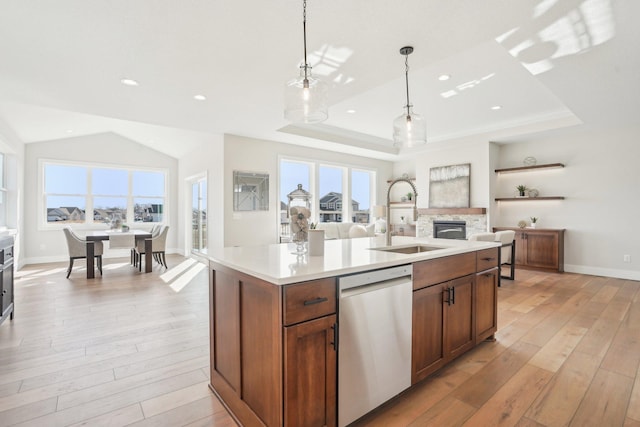 14147 77th Ln NE, Otsego, MN 55330 - kitchen with stainless steel dishwasher, a stone fireplace, light wood-style floors, light countertops, and decorative light fixtures