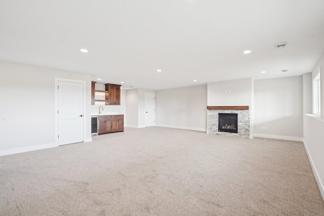 14147 77th Ln NE, Otsego, MN 55330 - unfurnished living room with recessed lighting, light carpet, bar with sink, a fireplace, and wine cooler