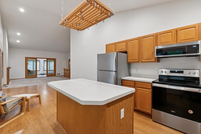 3406 Eagan Oaks Ct, Eagan, MN 55123 - kitchen with stainless steel appliances, light countertops, a kitchen island, open floor plan, and light wood finished floors