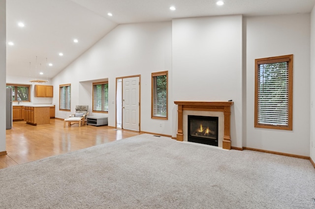 3406 Eagan Oaks Ct, Eagan, MN 55123 - living room with high vaulted ceiling, recessed lighting, a lit fireplace, light carpet, and light wood-type flooring