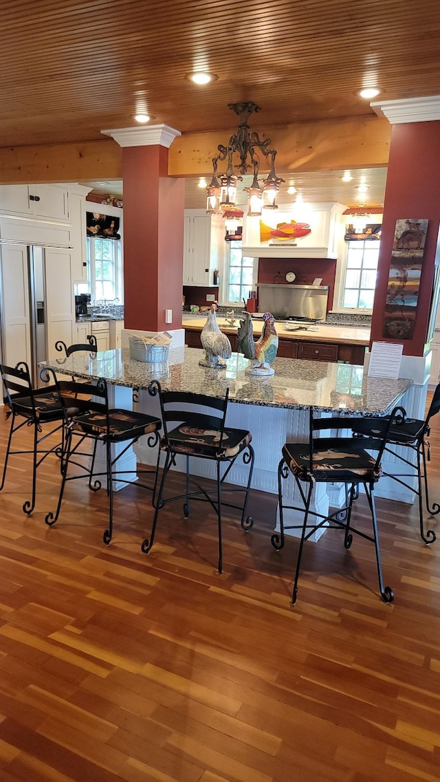 3307 Nokomis NE, Alexandria, MN 56308 - kitchen featuring white cabinetry, wood finished floors, a kitchen breakfast bar, and wood ceiling