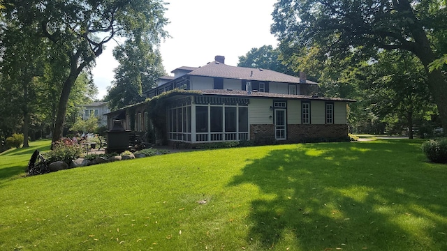 3307 Nokomis NE, Alexandria, MN 56308 - back of property with a sunroom, a yard, a chimney, and brick siding