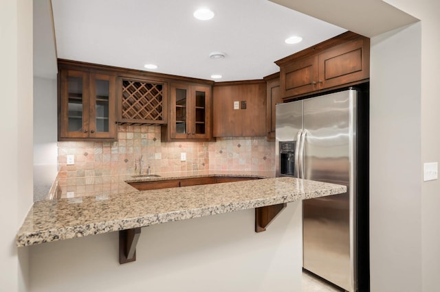 3153 Magnolia Dr, Medina, MN 55340 - kitchen with stainless steel refrigerator with ice dispenser, a peninsula, glass insert cabinets, a breakfast bar area, and light stone counters