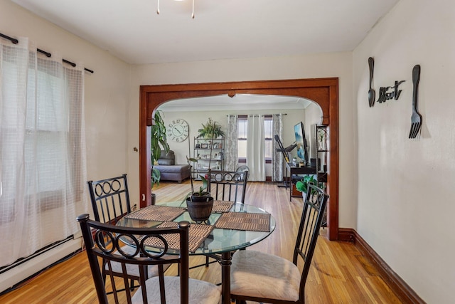 116 3rd Ave SE, Osseo, MN 55369 - dining space featuring a baseboard heating unit, arched walkways, and light wood-type flooring