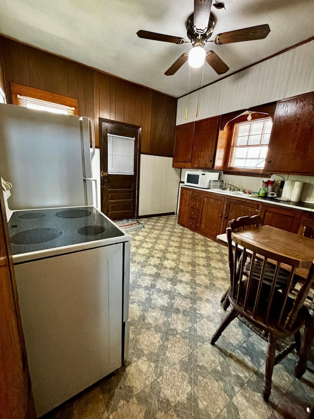 504 3rd Ave SE, Pipestone, MN 56164 - kitchen featuring white appliances, wooden walls, and ceiling fan