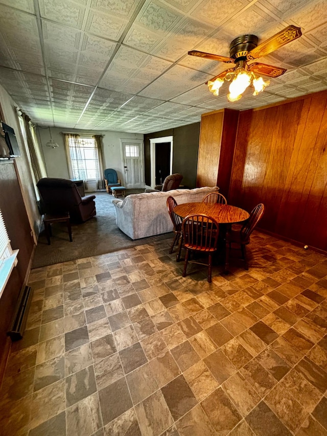 504 3rd Ave SE, Pipestone, MN 56164 - dining room with wood walls, a ceiling fan, and baseboard heating