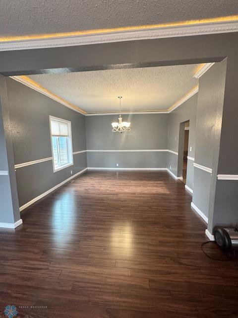 214 7th St, Hatton, ND 58240 - unfurnished room featuring crown molding, a textured ceiling, a chandelier, and dark wood-style flooring