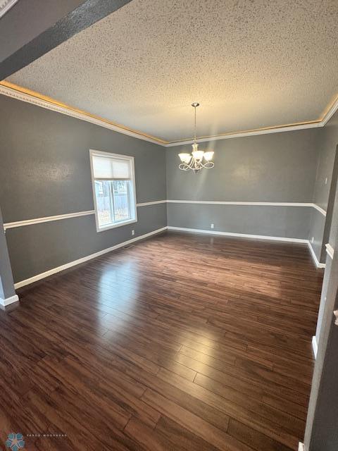 214 7th St, Hatton, ND 58240 - spare room with a textured ceiling, ornamental molding, a chandelier, and dark wood-type flooring