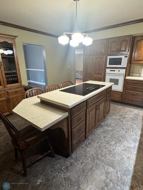 214 7th St, Hatton, ND 58240 - kitchen with white appliances, crown molding, a kitchen island, light countertops, and a breakfast bar