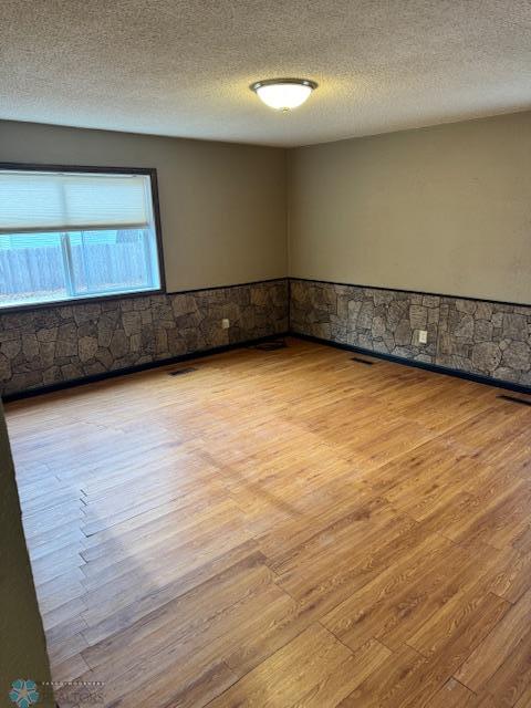 214 7th St, Hatton, ND 58240 - spare room with wood finished floors, wainscoting, and a textured ceiling