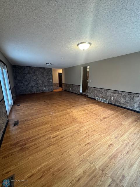 214 7th St, Hatton, ND 58240 - unfurnished living room with a wainscoted wall, wood finished floors, a textured ceiling, and a fireplace