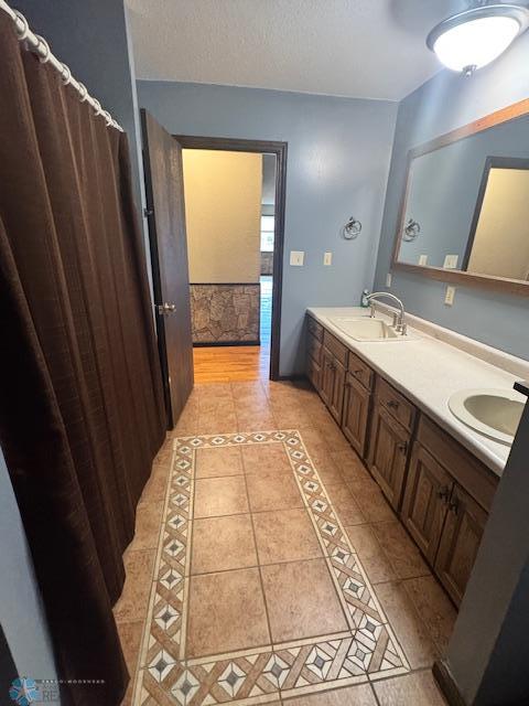 214 7th St, Hatton, ND 58240 - bathroom with tile patterned floors, double vanity, inlaid floor details, and a textured ceiling