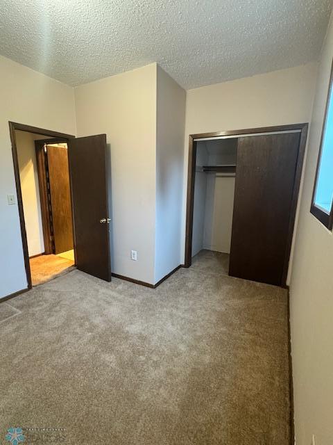 214 7th St, Hatton, ND 58240 - unfurnished bedroom with carpet flooring, a textured ceiling, and a closet