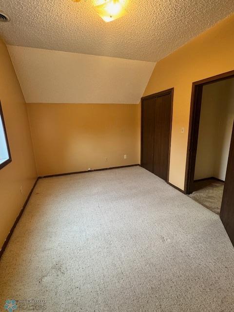 214 7th St, Hatton, ND 58240 - additional living space featuring light carpet, vaulted ceiling, and a textured ceiling
