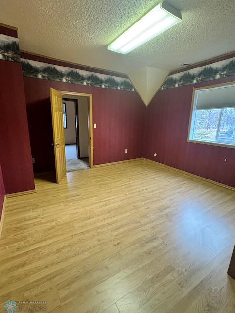 214 7th St, Hatton, ND 58240 - spare room with wood finished floors, a textured ceiling, lofted ceiling, and ornamental molding