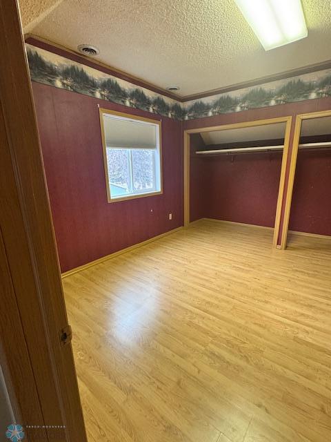 214 7th St, Hatton, ND 58240 - unfurnished bedroom with a textured ceiling, light wood-style flooring, and two closets