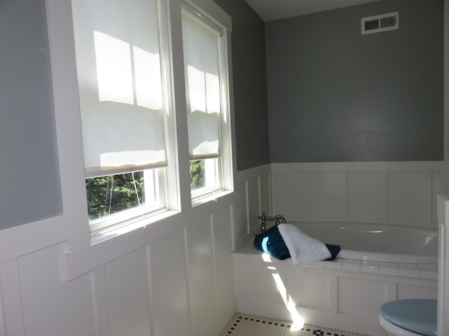 1504 4th St NE, Willmar, MN 56201 - bathroom with a bath, a decorative wall, tile patterned floors, and a wainscoted wall