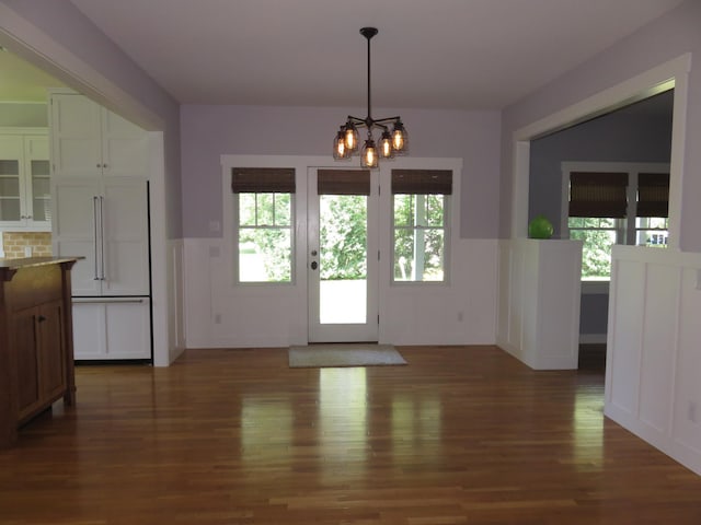 1504 4th St NE, Willmar, MN 56201 - unfurnished dining area with wainscoting, a chandelier, dark wood-style flooring, and a decorative wall