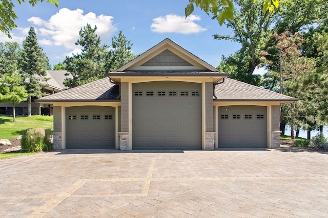 12795 Ozark Trl N, May Twp, MN 55082 - view of front of home featuring stone siding, a shingled roof, and decorative driveway