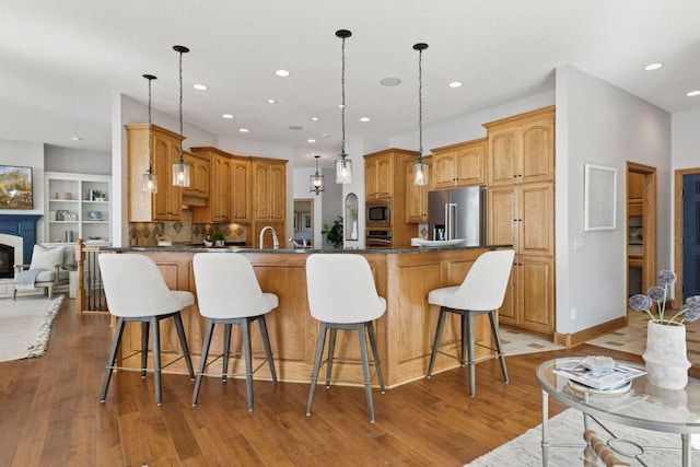 12795 Ozark Trl N, May Twp, MN 55082 - kitchen with stainless steel appliances, light wood-style floors, a kitchen breakfast bar, recessed lighting, and a glass covered fireplace