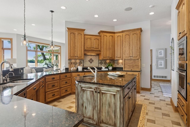 12795 Ozark Trl N, May Twp, MN 55082 - kitchen featuring stainless steel appliances, decorative backsplash, recessed lighting, a center island with sink, and dark stone countertops