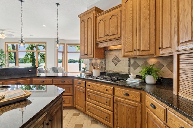 12795 Ozark Trl N, May Twp, MN 55082 - kitchen with stainless steel gas stovetop, tasteful backsplash, hanging light fixtures, and brown cabinets