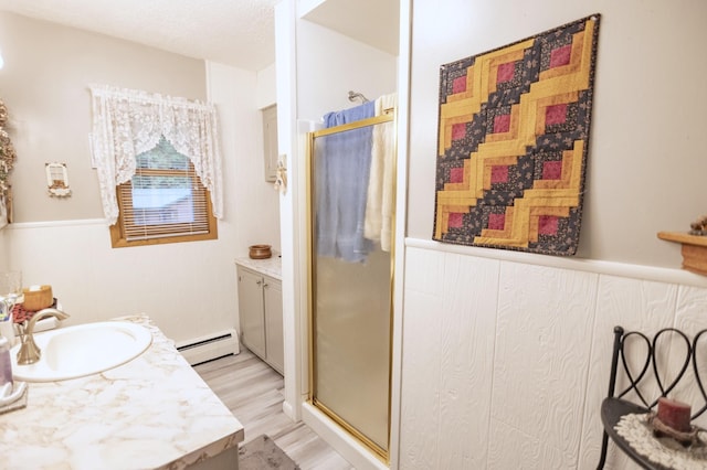 39070 County Highway 67, Newton Twp, MN 56567 - bathroom featuring vanity, a shower stall, a baseboard radiator, and wood finished floors