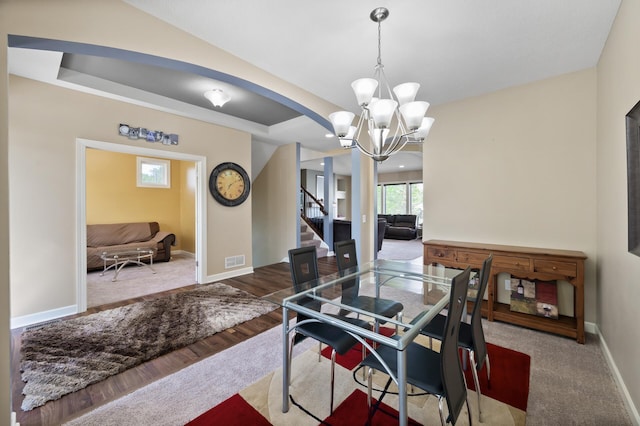 10412 Florida Ave N, Brooklyn Park, MN 55445 - dining space with a chandelier, stairs, arched walkways, wood finished floors, and a tray ceiling