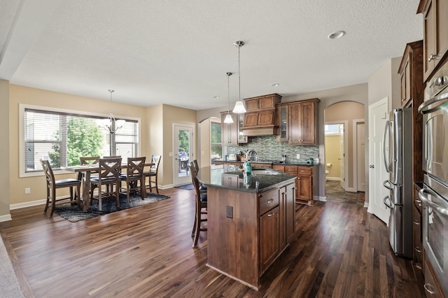 10412 Florida Ave N, Brooklyn Park, MN 55445 - kitchen featuring arched walkways, dark wood-style floors, stainless steel appliances, a kitchen bar, and a textured ceiling