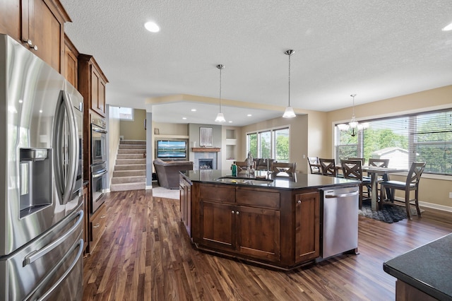 10412 Florida Ave N, Brooklyn Park, MN 55445 - kitchen featuring appliances with stainless steel finishes, dark countertops, dark wood-style floors, a fireplace, and a textured ceiling