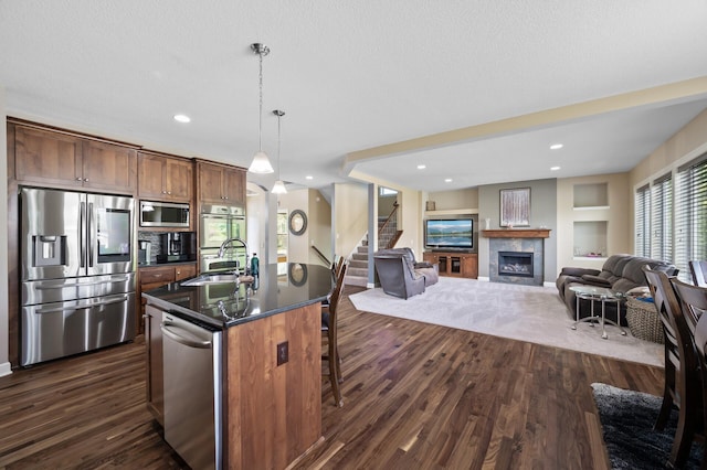 10412 Florida Ave N, Brooklyn Park, MN 55445 - kitchen with appliances with stainless steel finishes, dark countertops, a kitchen breakfast bar, a tile fireplace, and open floor plan