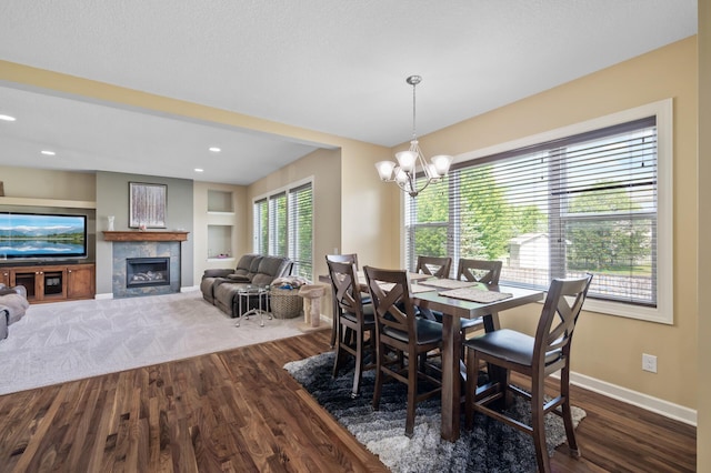 10412 Florida Ave N, Brooklyn Park, MN 55445 - dining area with dark wood-style flooring, a tiled fireplace, built in shelves, a chandelier, and recessed lighting