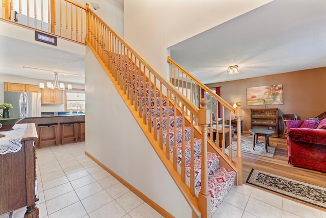 1405 17th Dr SW, Austin, MN 55912 - staircase with tile patterned flooring, a chandelier, and a towering ceiling