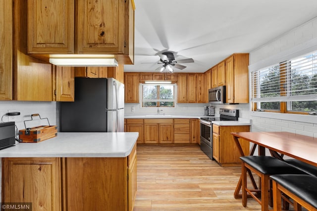 W10429 Hinker Rd, Foster Twp, WI 54493 - kitchen with appliances with stainless steel finishes, light wood-type flooring, light countertops, a ceiling fan, and brown cabinetry