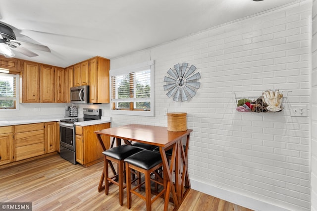 W10429 Hinker Rd, Foster Twp, WI 54493 - kitchen with appliances with stainless steel finishes, light countertops, light wood-style flooring, ceiling fan, and brick wall