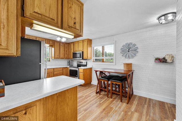 W10429 Hinker Rd, Foster Twp, WI 54493 - kitchen with stainless steel appliances, brick wall, light countertops, light wood-type flooring, and plenty of natural light