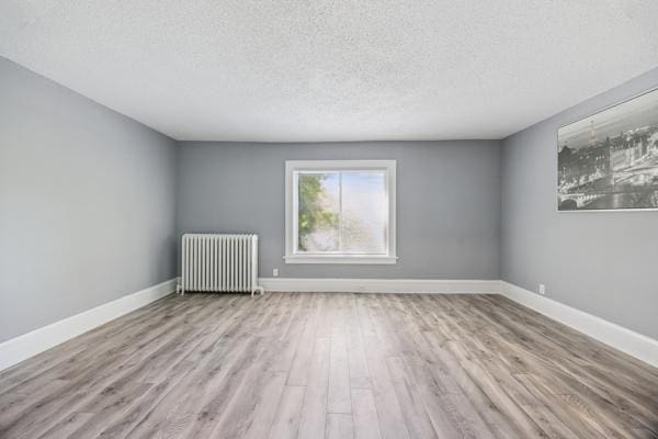 1711 Newton Ave N, Minneapolis, MN 55411 - empty room with radiator, a textured ceiling, and wood finished floors