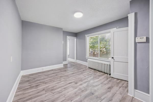 1711 Newton Ave N, Minneapolis, MN 55411 - empty room featuring radiator heating unit and wood finished floors