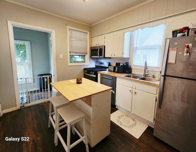 1033 Mark St, Winona, MN 55987 - kitchen featuring appliances with stainless steel finishes, crown molding, dark wood-type flooring, white cabinets, and tasteful backsplash