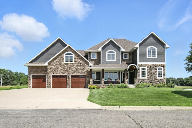 1570 Wood Duck Ln NE, Owatonna, MN 55060 - view of front of house featuring stone siding, concrete driveway, a front lawn, covered porch, and an attached garage