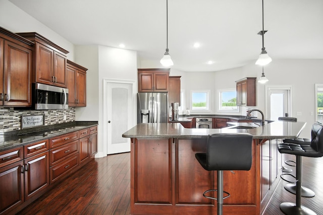 1570 Wood Duck Ln NE, Owatonna, MN 55060 - kitchen featuring appliances with stainless steel finishes, decorative backsplash, dark wood-type flooring, a breakfast bar, and recessed lighting
