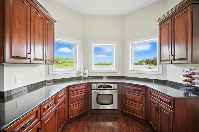 1570 Wood Duck Ln NE, Owatonna, MN 55060 - kitchen featuring stainless steel oven, dark wood finished floors, and dark stone counters