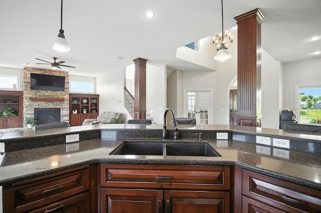 1570 Wood Duck Ln NE, Owatonna, MN 55060 - kitchen with decorative columns, open floor plan, a ceiling fan, a fireplace, and pendant lighting