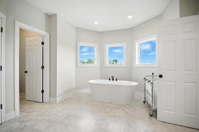1570 Wood Duck Ln NE, Owatonna, MN 55060 - bathroom featuring a freestanding bath, marble look tiles, and recessed lighting